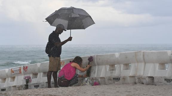 Eliagne Sanchez and K. Parker lay flowers on the beach near the partially collapsed building.