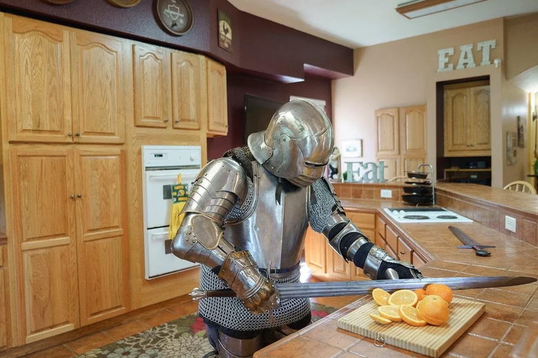 A knight slicing oranges in a large kitchen.